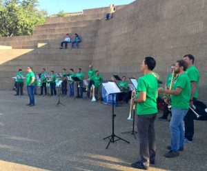 Symphony musicians perform in green union t-shirts at a public park