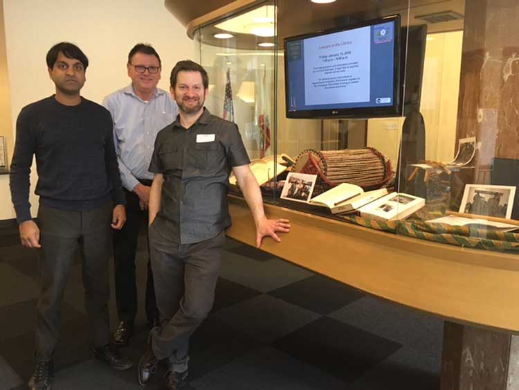 Scholars of law and music stand next to a glass case exhibit