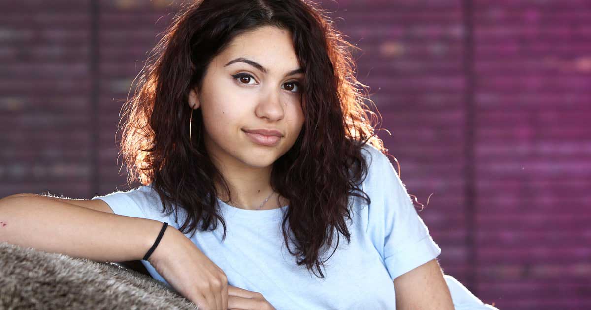 Looking younger than her 21 years, Alessia Cara slouches in a white t-shirt.