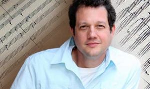 Michael Giacchino portrait with background of sheet music