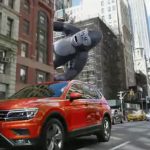 Red Volkswagen Tiguan is tailed by an inflatable gorilla.