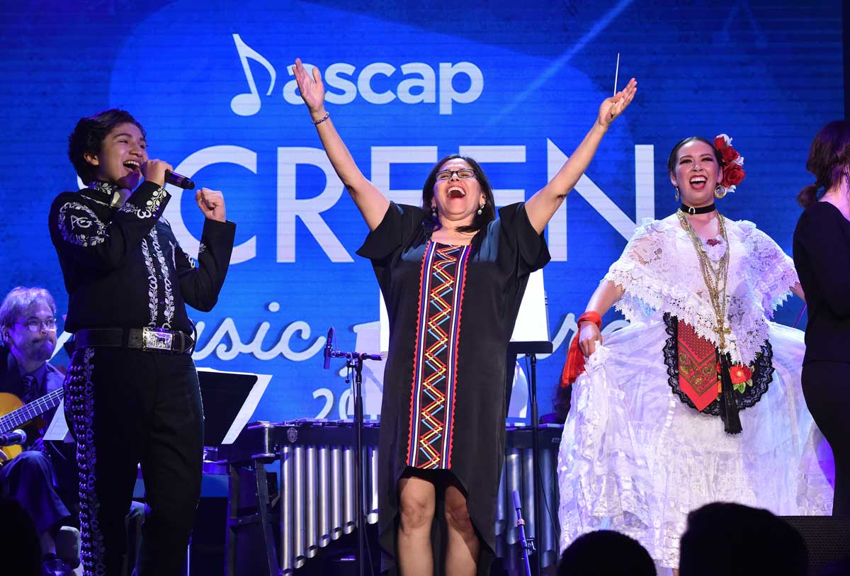 Germaine Franco, center, strikes a triumphant pose with hands raised to the sky.