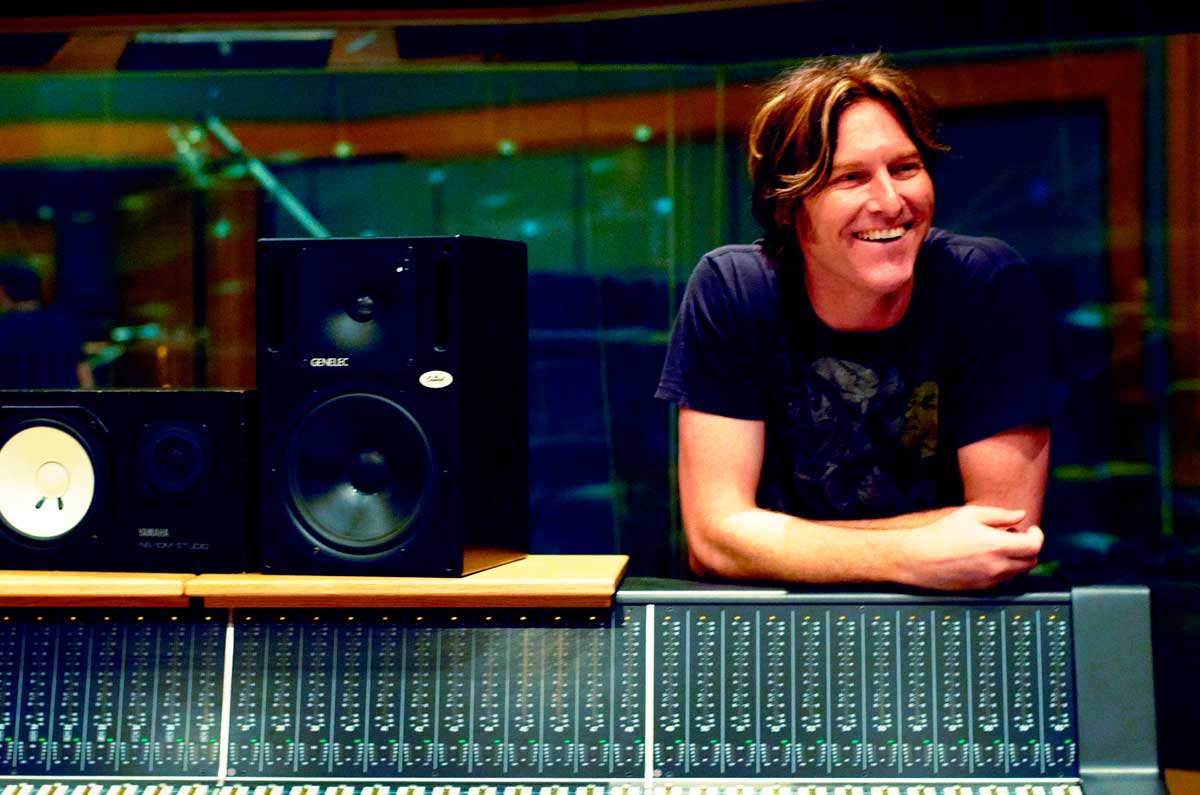 Composer Tyler Bates looks boyishly handsome as he leans on a sound mixing board and smiles.