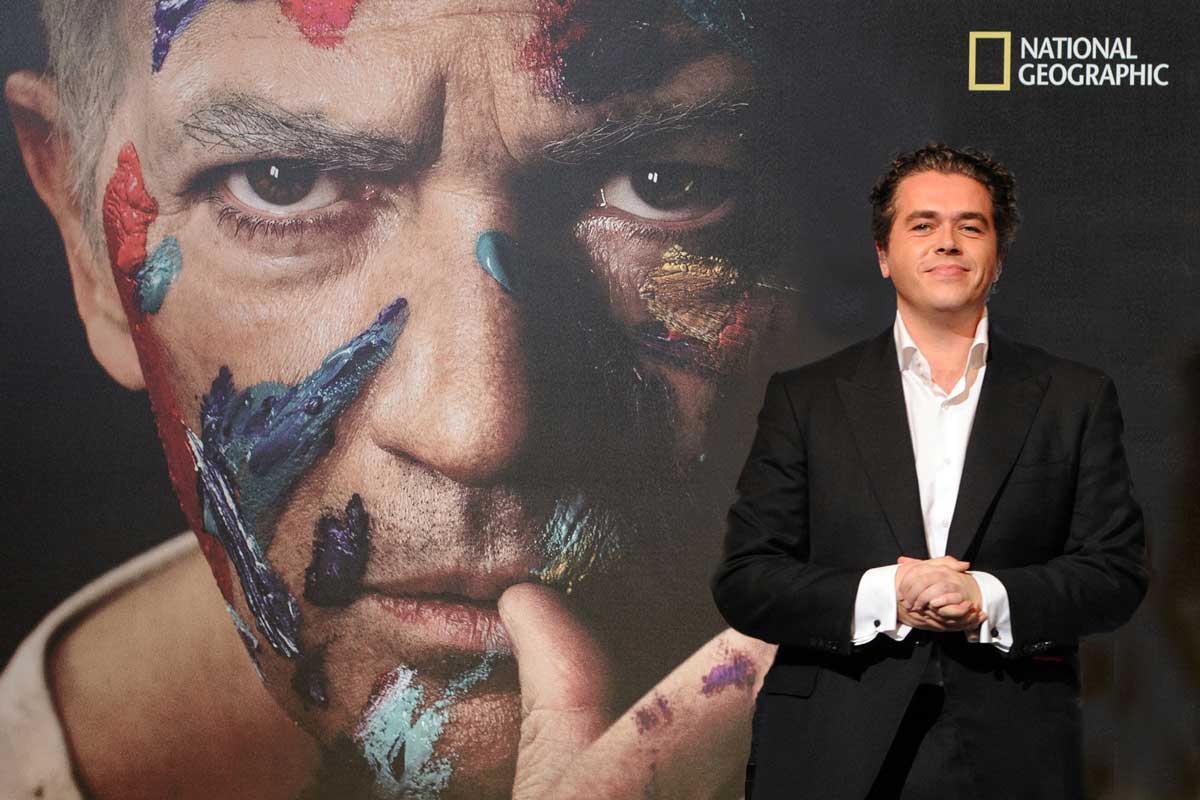 Lorne Balfe stands in front of a giant photo of Antonio Banderas as Picasso