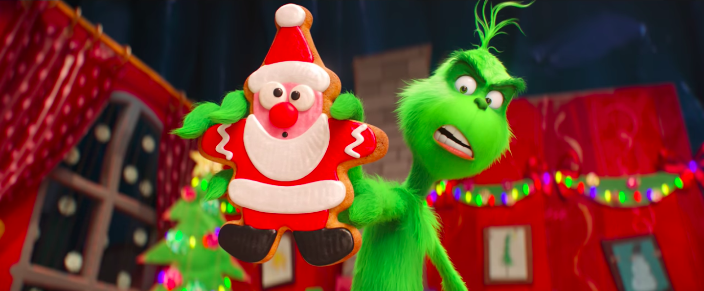 The Grinch thrusts a Santa cookie.