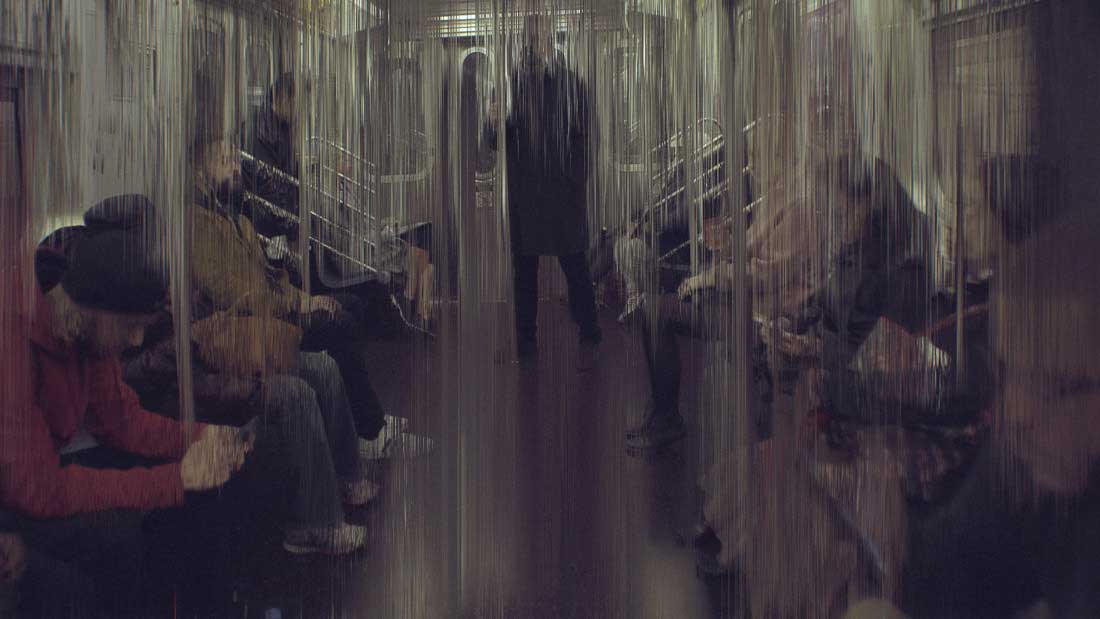 People in a subway car that look like they're behind a wall of glass streaked by liquid data